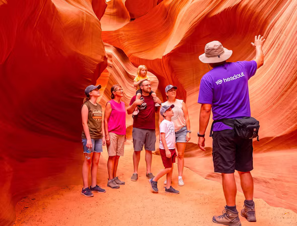 A guided canyon tour group exploring a red rock slot canyon