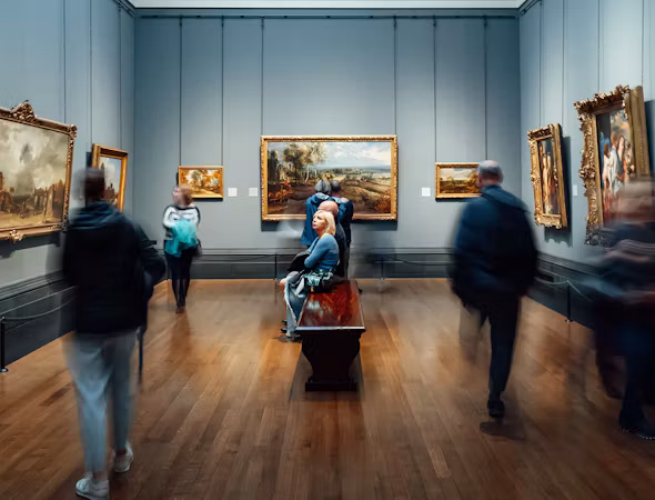 Visitors admiring paintings in a classic art gallery